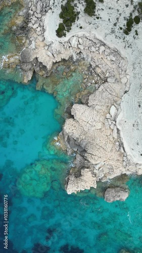 A breathtaking drone shot reveals a clear ocean and coast of island in Greece, vertical drone shot