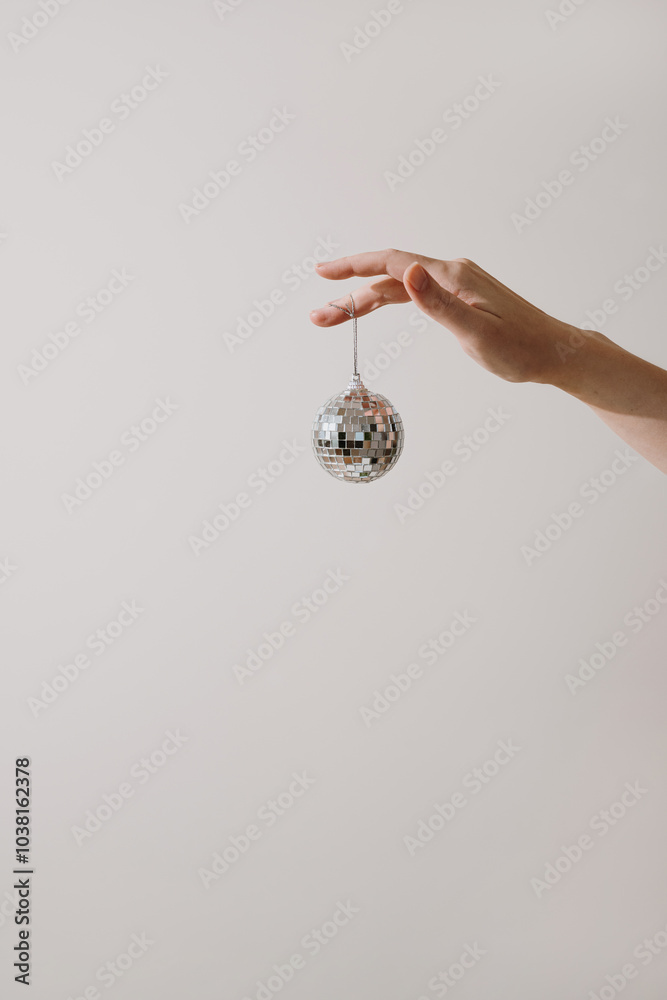 Holding a Mini Disco Ball Against Simple Background. Retro Party Theme, Dance Music Icon, Minimalist Style, Celebration Symbol, Nostalgic Decor Holding a Mini Disco Ball Against Simple Background. Retro Party Theme, Dance Music Icon, Minimalist Style, Celebration Symbol, Nostalgic Decor