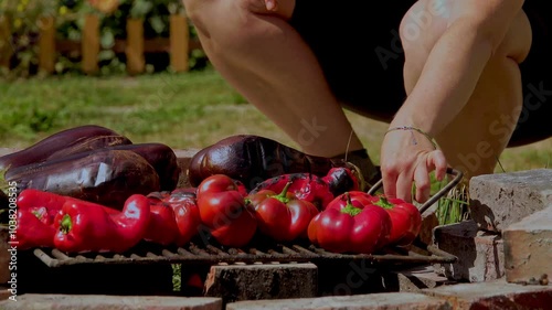 A rustic outdoor scene of vegetables grilling over a wood fire, an essential step in making traditional Romanian zacusca. The fire-roasted vegetables bring out deep, smoky flavors photo