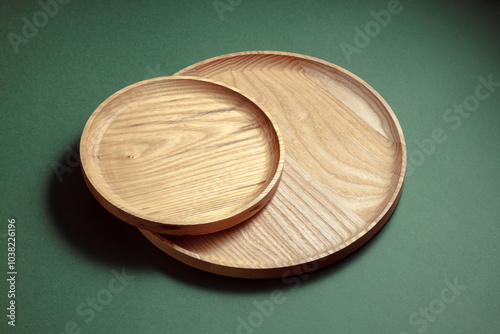 Wooden flat plates on a green background. The concept of ecological tableware. Products for modern kitchen. Zero emissions. photo