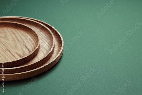 Wooden flat plates on a green background. The concept of ecological tableware. Products for modern kitchen. Zero emissions. photo