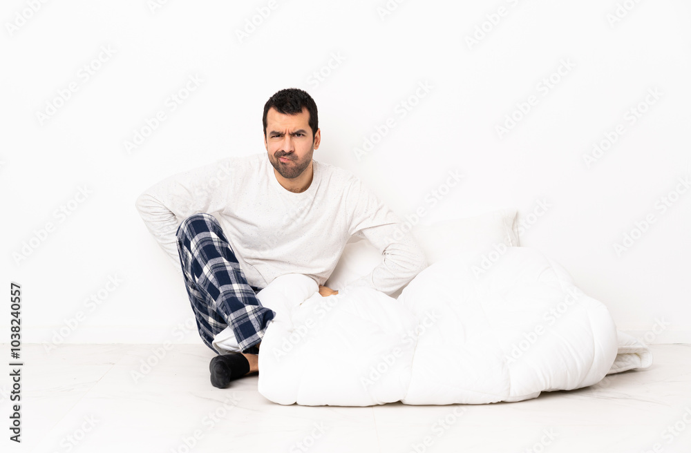 Caucasian man in pajamas sitting on the floor at indoors angry Caucasian man in pajamas sitting on the floor at indoors angry