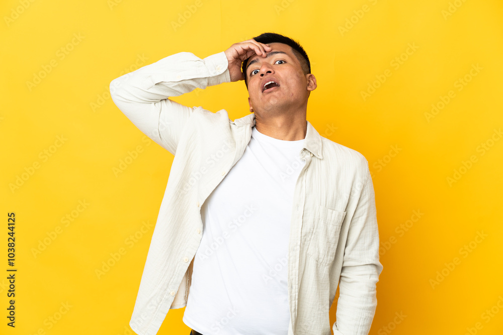Young Ecuadorian man isolated on yellow background doing surprise gesture while looking front Young Ecuadorian man isolated on yellow background doing surprise gesture while looking front