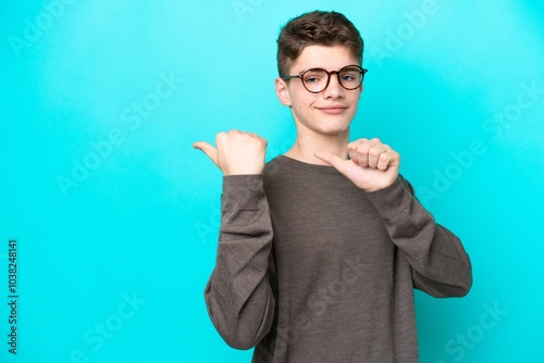 Teenager Russian man isolated on blue background pointing to the side to present a product