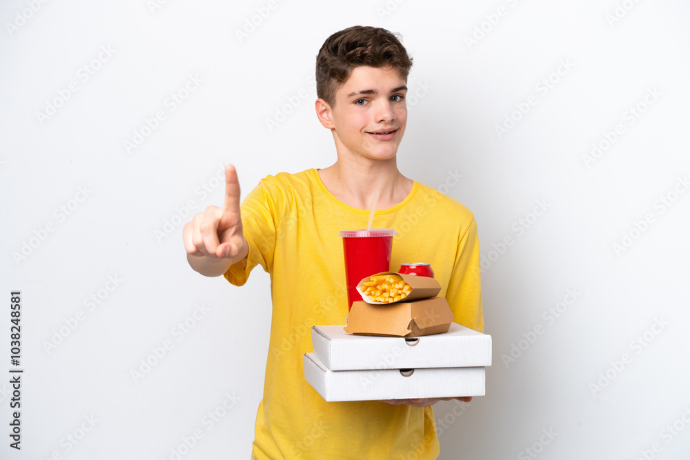 Teenager Russian man holding fast food isolated on white background showing and lifting a finger Teenager Russian man holding fast food isolated on white background showing and lifting a finger