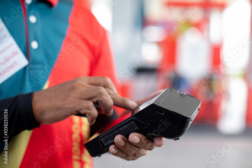 Hand of cashier hold credit card reader with blurry gas station background. Credit card payment. Buy and sell products & service. The concept of payment in gas station. photo