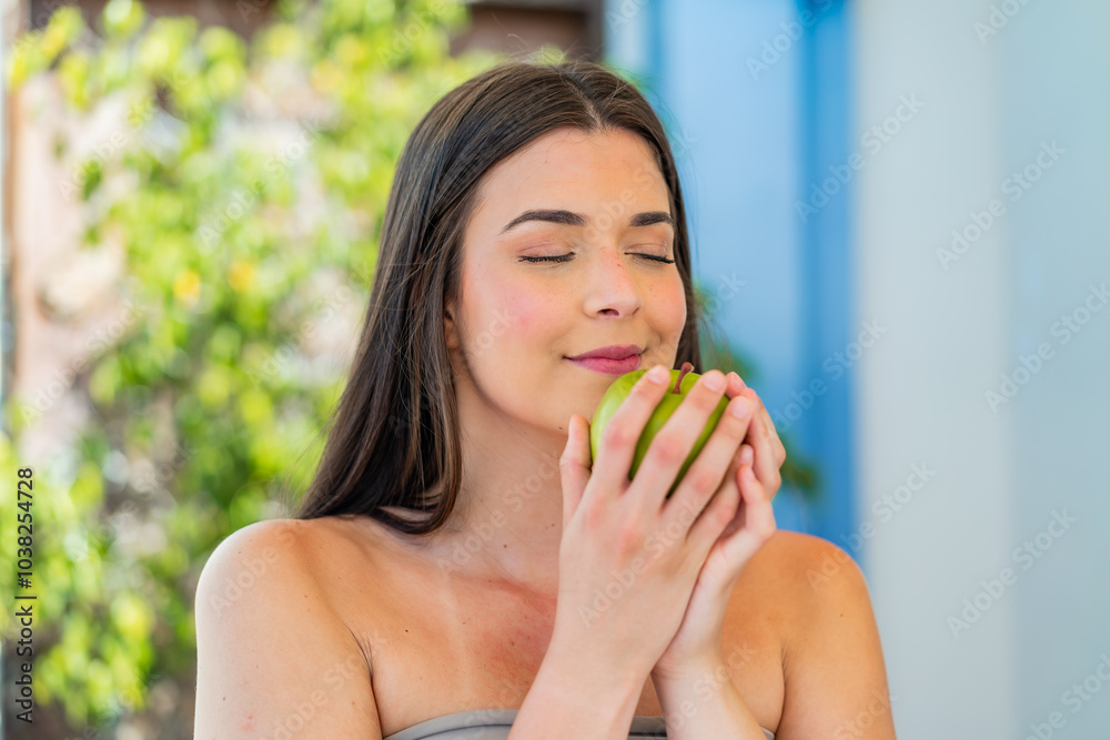 Young pretty Brazilian woman at outdoors holding an apple Young pretty Brazilian woman at outdoors holding an apple