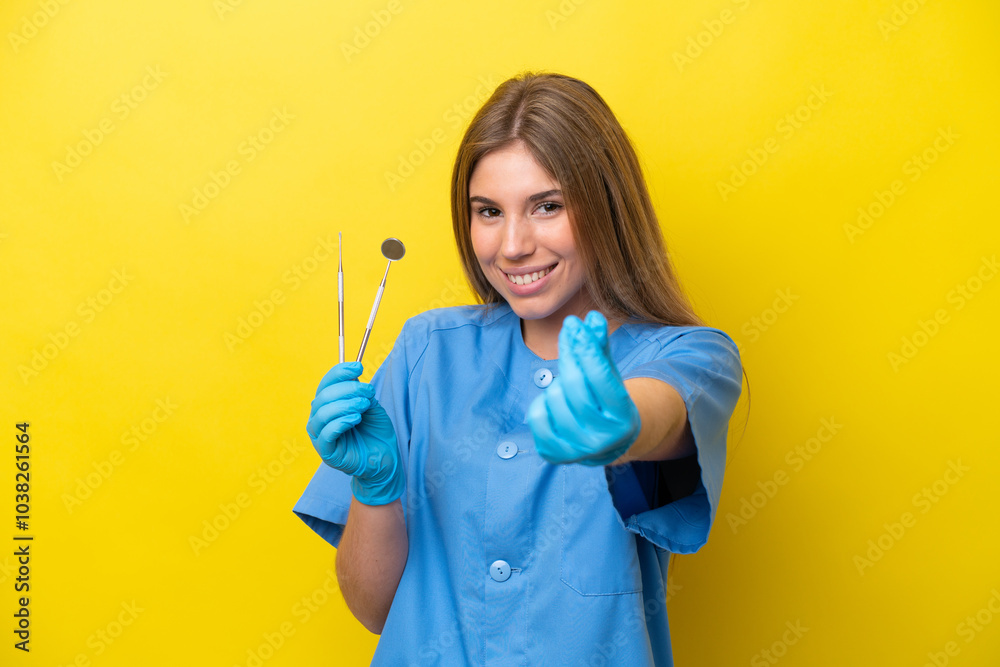 Dentist caucasian woman holding tools isolated on yellow background making money gesture Dentist caucasian woman holding tools isolated on yellow background making money gesture