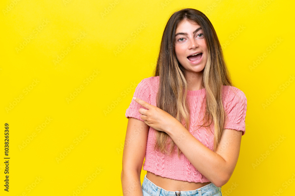 Obraz premium Young caucasian woman isolated on yellow background surprised and pointing side