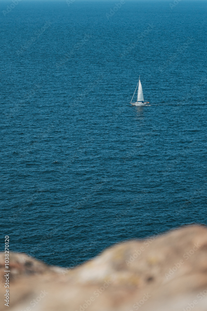 Fototapeta premium Small sailboat moves through clear and calm waters near Swedish coast in Baltic sea
