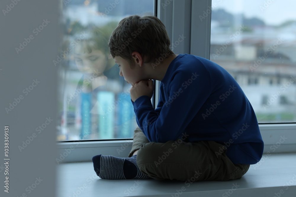 Fototapeta premium Autism concept. Lonely little boy near window at home