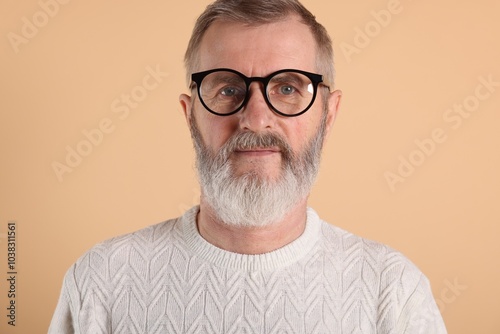 Portrait of senior man in glasses on beige background