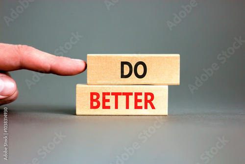 Do better symbol. Concept words Do better on beautiful wooden blocks. Beautiful grey background. Businessman hand. Business and do better concept. Copy space.