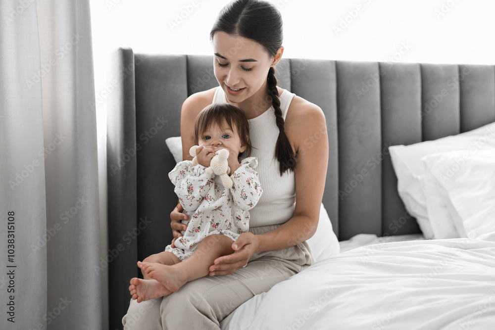 Beautiful young mother and her cute little baby with rabbit toy on bed at home Beautiful young mother and her cute little baby with rabbit toy on bed at home