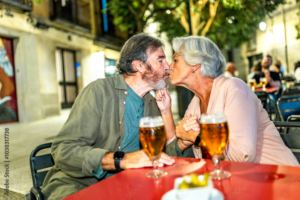 Senior couple kissing while drinking beer in an outdoor terrace Senior couple kissing while drinking beer in an outdoor terrace