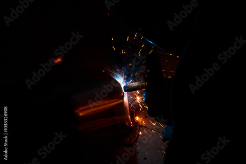 Arc welding. Welding pipes in inert gases. MIG / MAG. A bright flash of light and a sheaf of sparks.