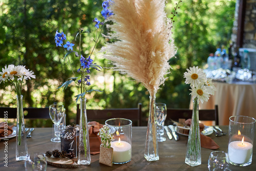 Wedding decoration. Floristics. Vessels with candles and bulk wax. Transparency and ease of design. Blue flowers and pampas.