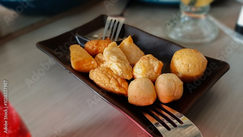 Delicious Assorted Fish Balls, Shrimp Balls, Kekian, Batagor, Pempek, Dimsum, Fried Dumplings on Black Square Plate, Popular Asian Street Food Platter, Restaurant Style, Blur Background Presentation photo