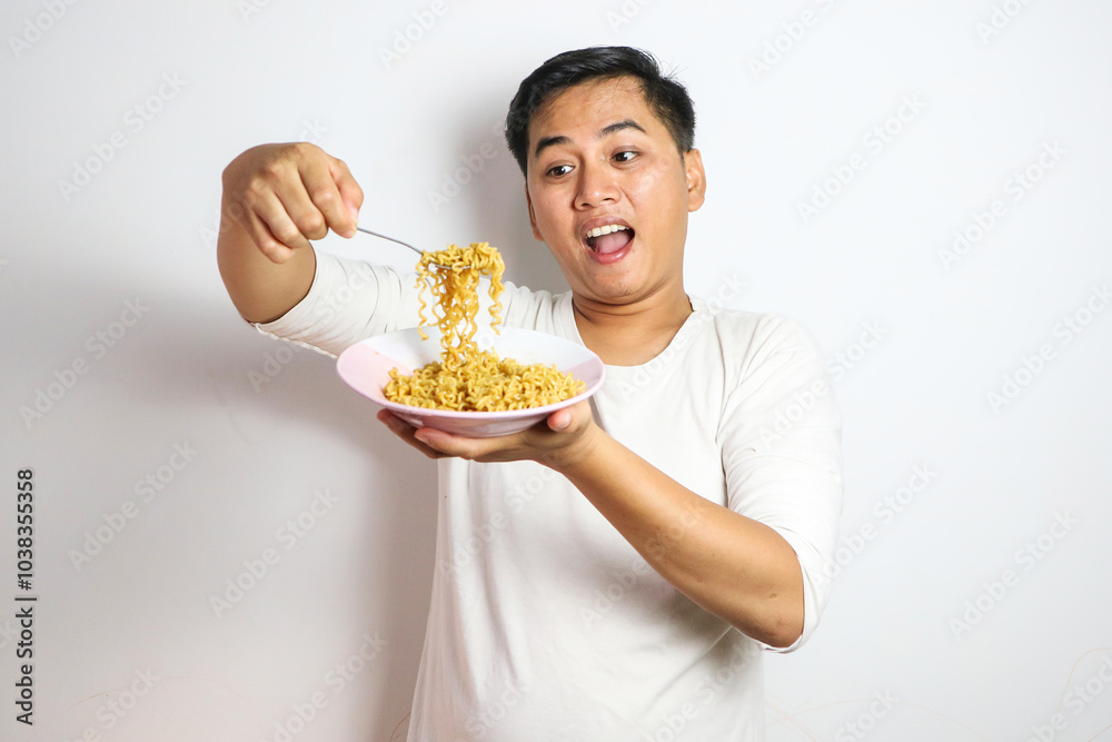 Adult Asian man showing surprised expression while eating noodle Adult Asian man showing surprised expression while eating noodle