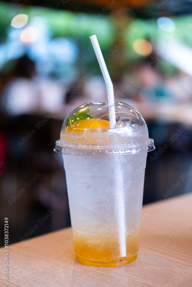 A cup of peach soda on the table, with bokeh background of the cafe