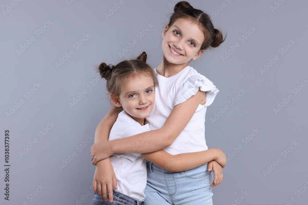 Portrait of cute little sisters on grey background Portrait of cute little sisters on grey background