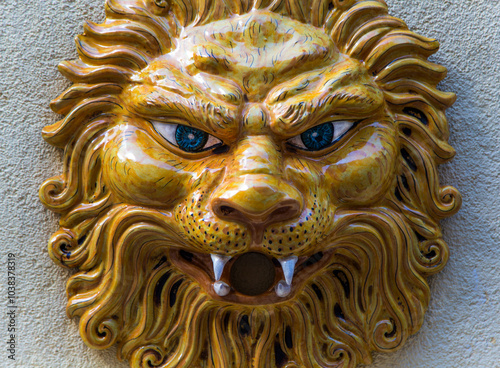 Intricately designed lion's head plaque captivates onlookers in Taormina, Sicily, blending artistry and history against a textured wall backdrop photo