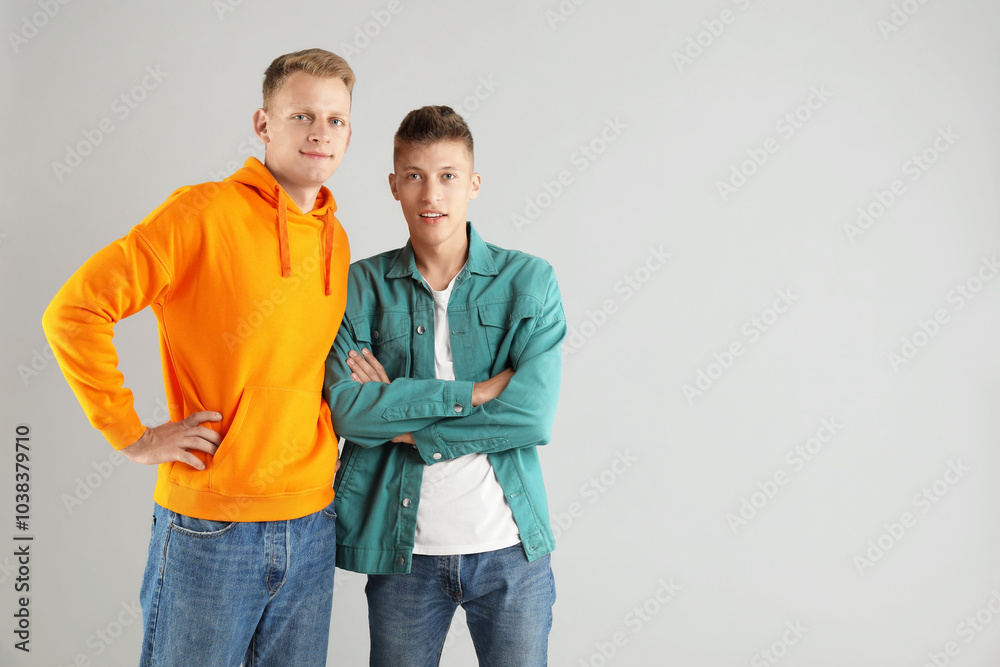 Two happy brothers posing on light background. Space for text Two happy brothers posing on light background. Space for text