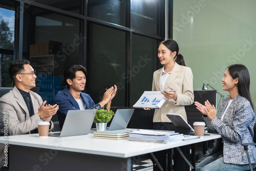 Asian businessman showing hand and smiling young team of colleagues making good business discussion in modern coworking office concept teamwork people