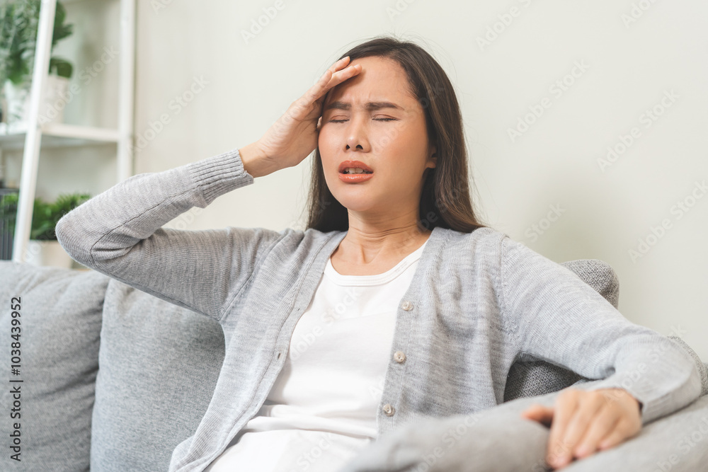 Dizzy asian young woman, girl headache or migraine pain suffering from vertigo while sitting on couch in living room at home, holding head with hand, health problem of brain or inner ear not balance. Dizzy asian young woman, girl headache or migraine pain suffering from vertigo while sitting on couch in living room at home, holding head with hand, health problem of brain or inner ear not balance.