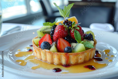 A beautifully plated gourmet fruit tart, topped with fresh berries and kiwi slices, placed on a white plate with a drizzle of honey and mint garnish photo