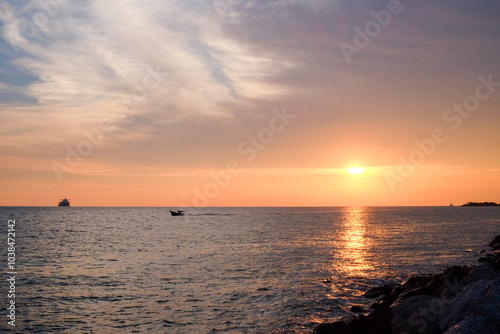 Serene Sunset Over the Strait of Malacca with Silhouetted Boat and Gentle Waves photo