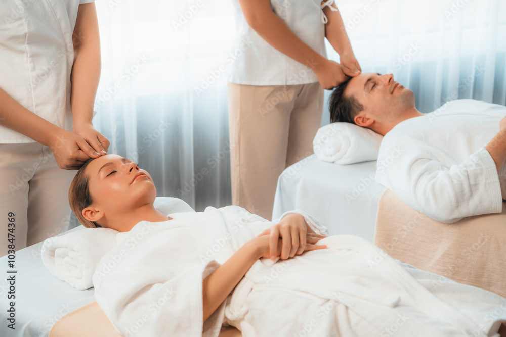 Caucasian couple enjoying relaxing anti-stress head massage and pampering facial beauty skin recreation leisure in dayspa modern light ambient at luxury resort or hotel spa salon. Quiescent Caucasian couple enjoying relaxing anti-stress head massage and pampering facial beauty skin recreation leisure in dayspa modern light ambient at luxury resort or hotel spa salon. Quiescent