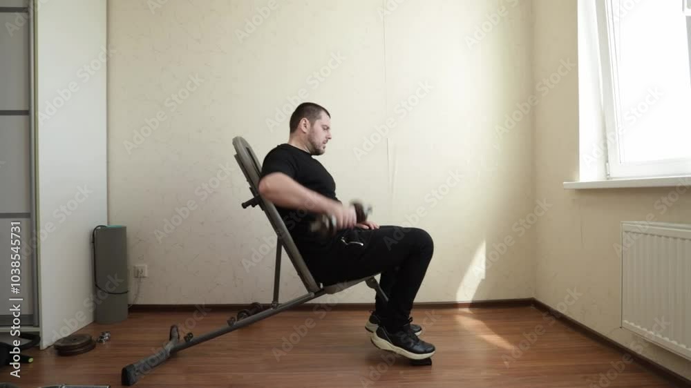 Man exercising in home gym, lifting dumbbells during his fitness routine, building muscle strength with indoor training equipment. Man exercising in home gym, lifting dumbbells during his fitness routine, building muscle strength with indoor training equipment.