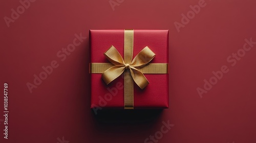 A luxurious red gift box with a golden ribbon neatly tied on top, creating an elegant and festive presentation on a clean background.