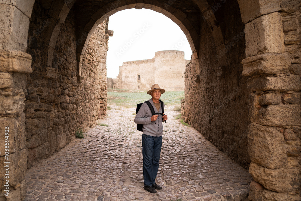 Retired traveler visits ancient fortress, soaking in historical grandeur and enjoying tranquil surroundings of ancient ruins during a peaceful autumn journey Retired traveler visits ancient fortress, soaking in historical grandeur and enjoying tranquil surroundings of ancient ruins during a peaceful autumn journey