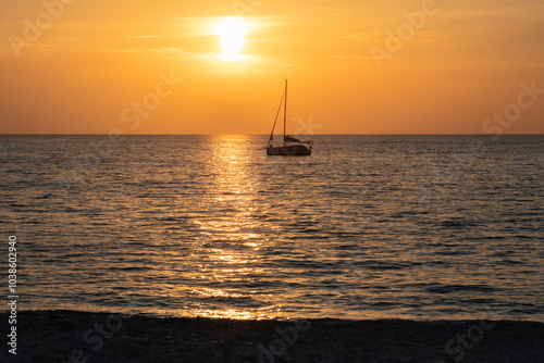 Beautiful sunset at Porto de Piana, Corsica. Silhouette of sailboat against orange sky