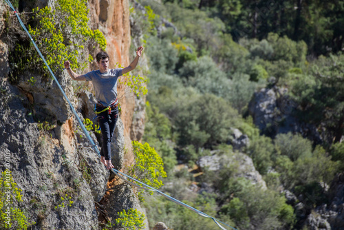 A tightrope walker walks along a cable stretched over a canyon.