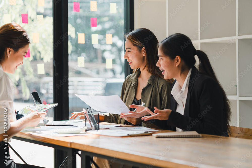 Three women engaged in lively discussion while reviewing documents at modern office table, showcasing collaboration and teamwork Three women engaged in lively discussion while reviewing documents at modern office table, showcasing collaboration and teamwork