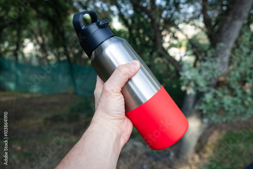 The man is holding a thermos flask. Camping gear concepr. Camping in nature.