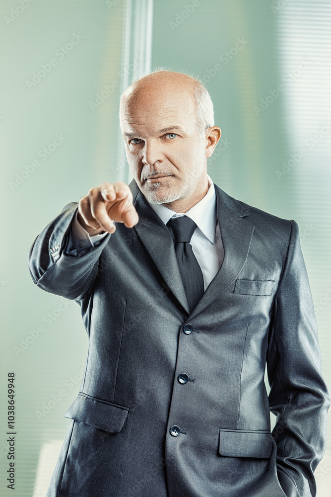 Serious businessman pointing with finger in office building Serious businessman pointing with finger in office building