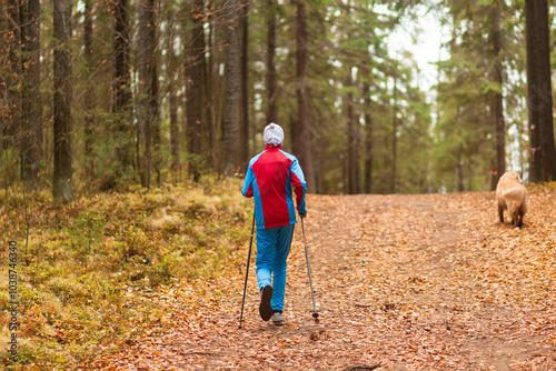 A man is doing Nordic walking in an autumn park. Doing sports outside.