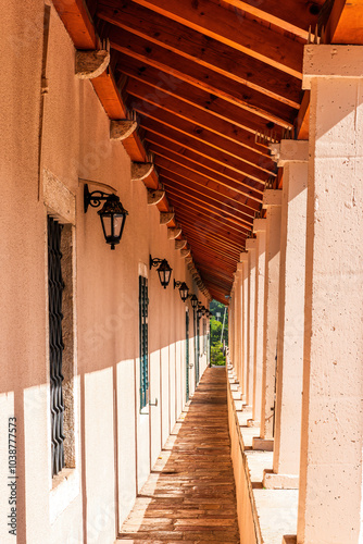 long gallery passage from a balcont syde of building to outdoor with beautiful white columns, windows and wooden brown roof. Vintage architecture concept photo