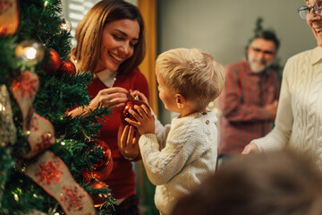 Happy family decorating christmas tree at home