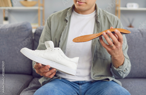 Fotografie Close up of an orthopedist man inserting an insole into a shoe