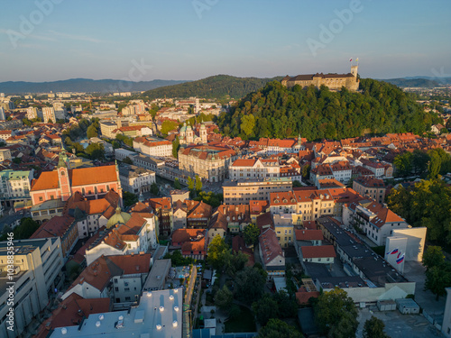 Ljubljana old town with Cathedral at Presernov trg square and Tromostovje bridges. Aerial view towards beautiful castle on the hill with the flags at sunset. Slovenian capital city at golden hour. photo