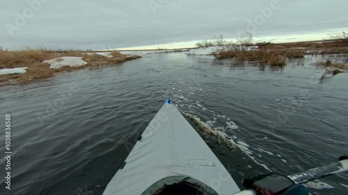 A kayak peacefully navigates a snow-covered river, capturing the serene beauty of winters icy landscape