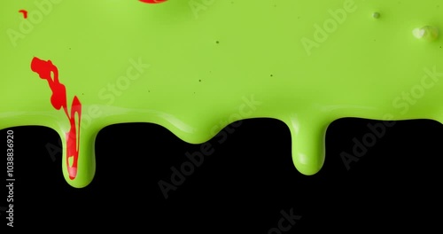 bichromatic liquid pigments of red and green pouring and dripping across a black background, vibrant colours and contrasts creating dynamic movement photo