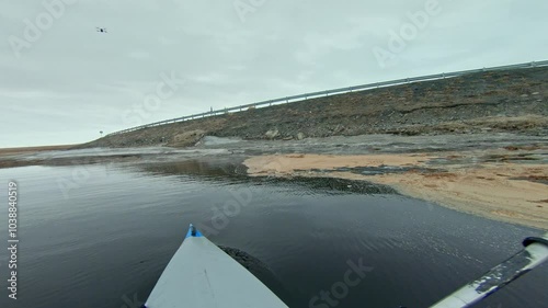POV GoPro footage of kayaking on spring water with ice and snow with a highway in the background