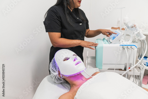 Beautician preparing led light therapy facial treatment for woman photo