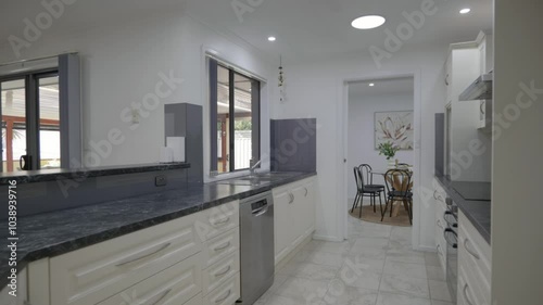 Magnificent white furnished kitchen with silver-golden details, marble countertop, and oven.